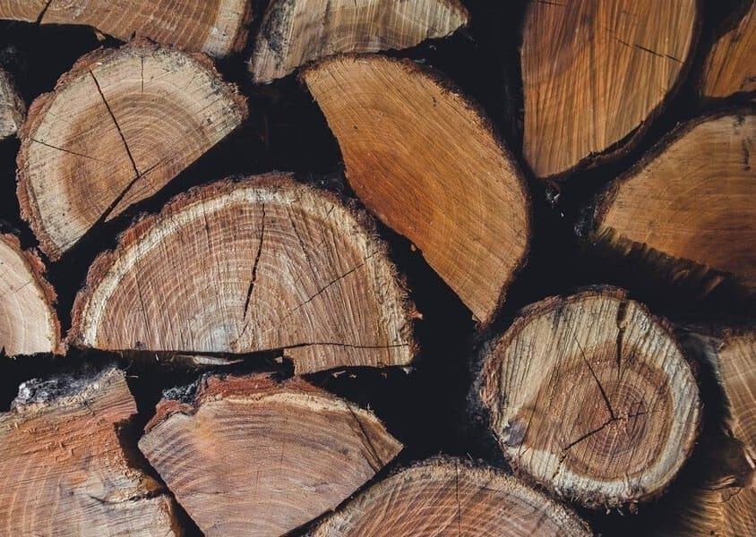 Stacked timber in the workshop yard, reclaimed and FSC-certified woods ready for the bench
